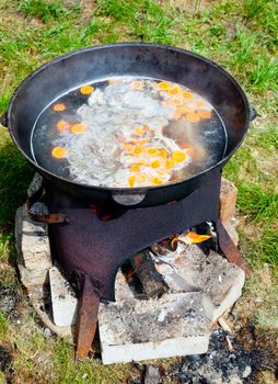 Chorba soup being made in kazan suspended above a fire using a metal frame