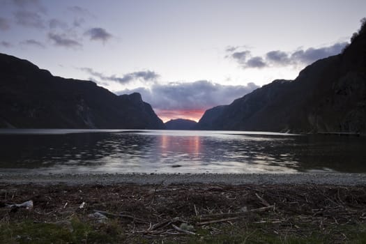 evening view over fjord in norway with cloudy sky and steep coast