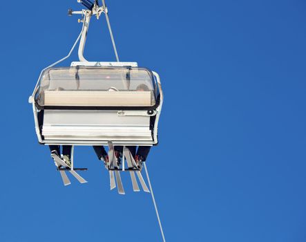 Chair lift with skiers at ski resort against blue sky