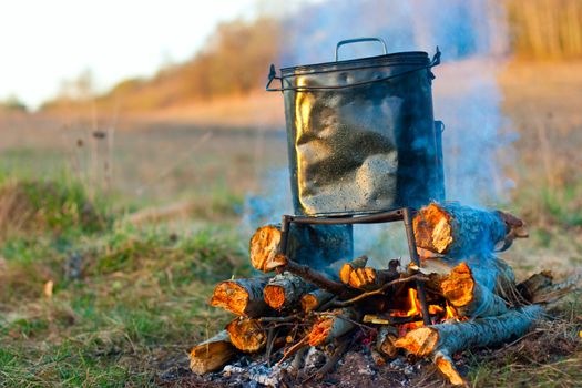 Camping kettle over burning campfire in the morning light