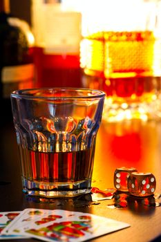 Glass of whiskey with dice and playing cards, shallow DOF