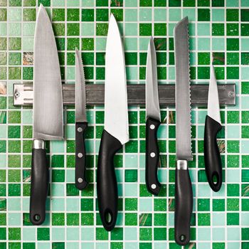 Kitchen knives on green mosaic wall