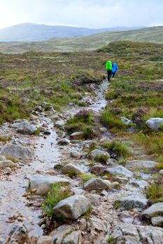 Two loaded hikers walking on a public track at National Park in Scotland