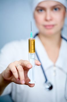 Doctor holding big syringe with yellow liquid, focus on syringe