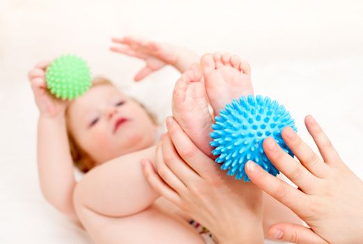Masseur massaging child's feet with rubber device, shallow focus
