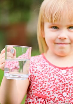 Little girl holding mug of water outdoors