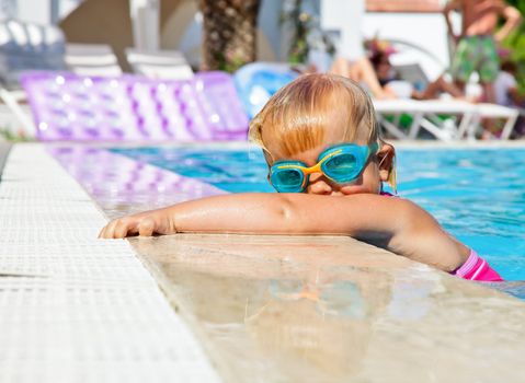 Little girl wearing swimming goggles in a hotel pool