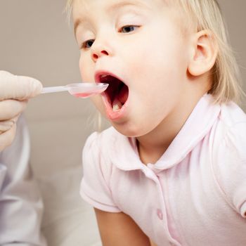 Doctor giving a spoon of syrup to little girl