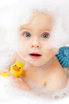 Cute little baby girl bathing in soapsuds