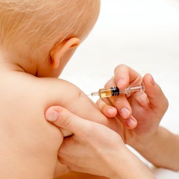 Doctor giving a child an intramuscular injection in arm, shallow DOF