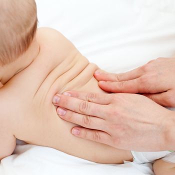 Masseuse massaging little baby girl, shallow focus