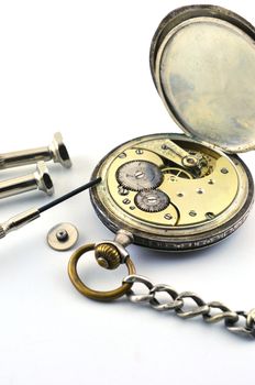 The old silver watch and a screwdriver to repair on the table, against a white background