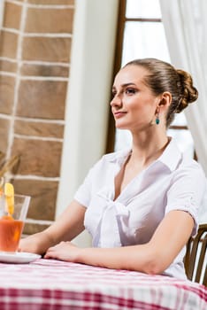 portrait of a nice lady in a restaurant, sitting with one cocktail at the table and waiting