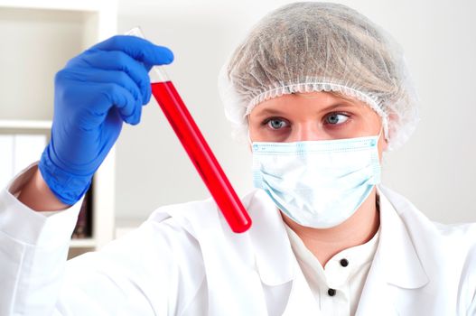 female chemist mixing liquids in test tubes, working in lab