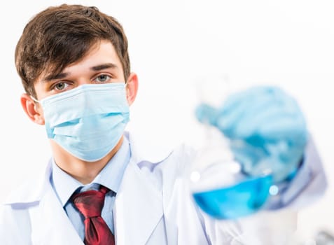 Portrait of a scientist working in the lab examines a test tube with liquid