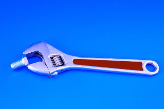 Wrench with adjustable bolt photographed against a blue background