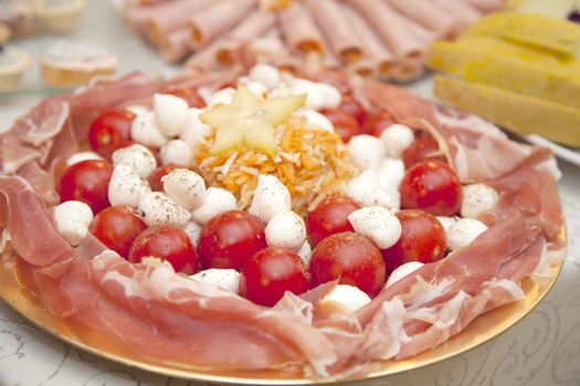 Catering food at a wedding party, plate with cherry tomato, prosciutto and cheese