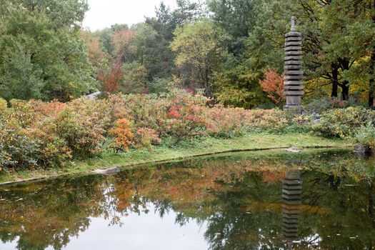 Autumn park with pond and decorative stone pagoda
