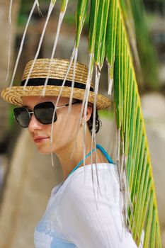 Woman in sunglasses near palm tree wearing hat