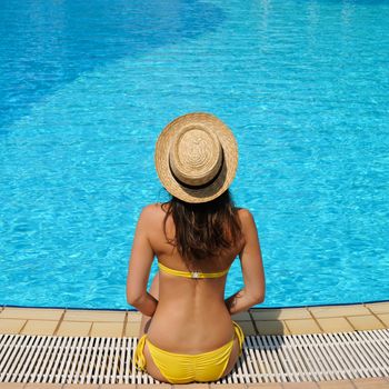 Woman in hat relaxing at the pool 