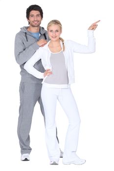 Couple wearing tracksuits pointing off camera