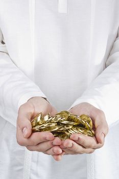 Close-up photograph of man's hands holding golden coins.