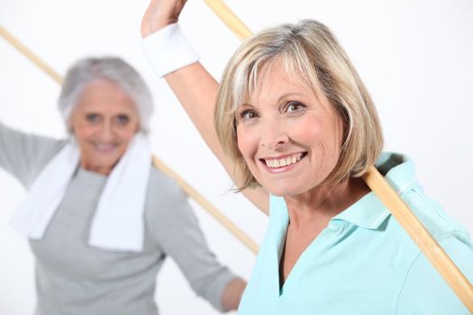 Elderly women stretching with wooden pole