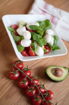 Tomato, avocado and basil salad on the table