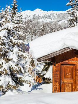 Alpine landscape. Snow-covered house, mountains, forest. Tyrol, Austria