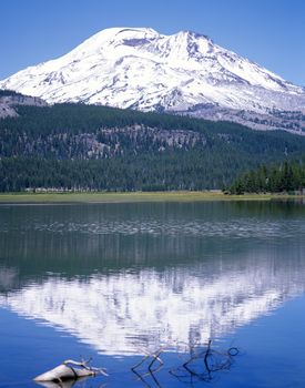 Mountain in Cascades range in Oregon reflected in a lake with a clear blue sky