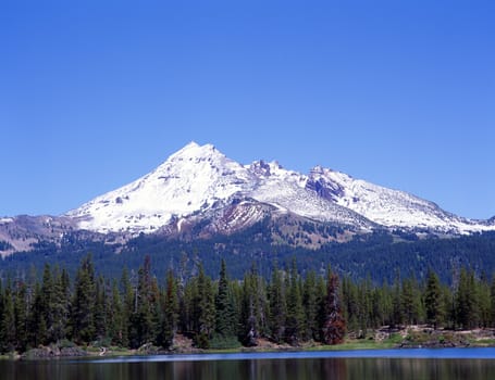 Mountain in Cascades range in Oregon reflected in a lake with a clear blue sky