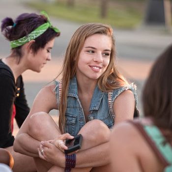 Pretty young teenage girl holding phone and smiling