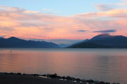 Panoramic view of Lake Garda, with colorful sunset over the mountains. Shot near the coast of Sirmione.