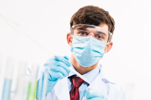 Portrait of a scientist working in the lab examines a test tube with liquid