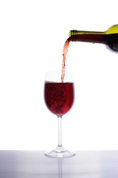 Red wine pouring into wine glass isolated on white background