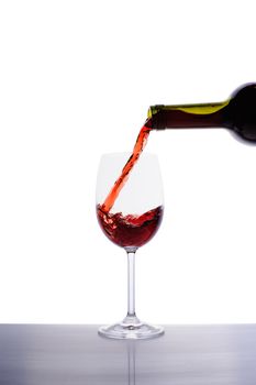 Red wine pouring into wine glass isolated on white background