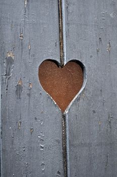 Heart-shaped cut on old wooden door.