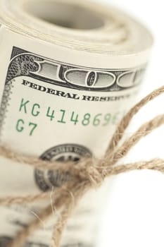 Roll of One Hundred Dollar Bills Tied in Burlap String Isolated on a White Background.