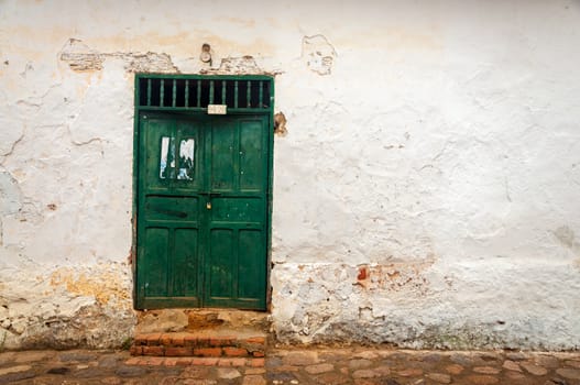 An old green door and white wall in a small colonial town in Colombia