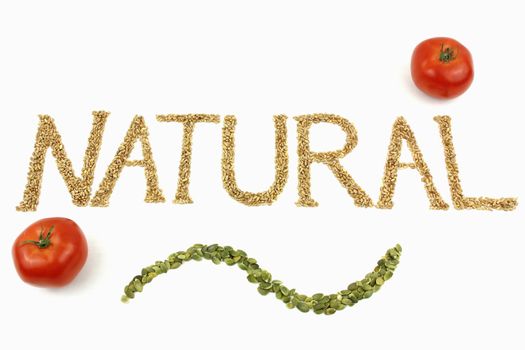 Natural written with wheat kernels, tomatoes and pumpkin seeds on white background
