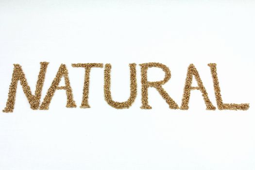 Natural written with wheat kernels on white background
