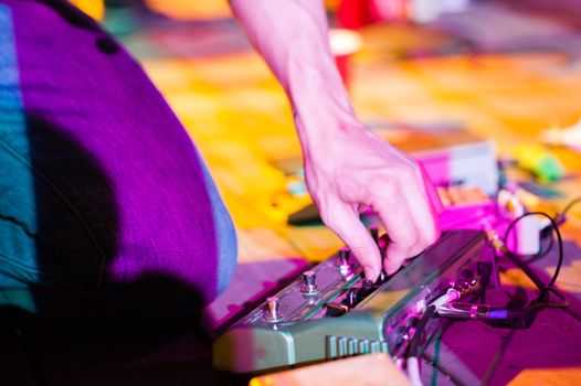 Musician adjusting effects pedal live on stage