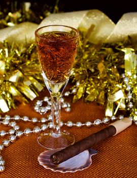 Crystal glass with brandy, cigars and Christmas decorations on a black background
