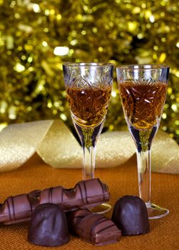 Crystal glasses of brandy and chocolate on the background of holiday lights.
