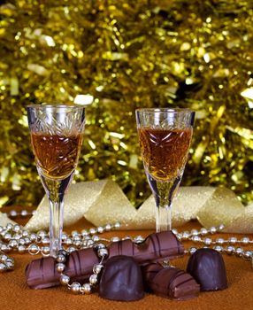 Crystal glasses of brandy and chocolate on the background of holiday lights
