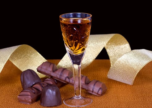 Crystal glass with cognac, chocolate and gold ribbon to mark the holiday
