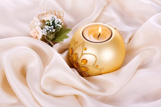 Holiday candle and flowers against a background of silk
