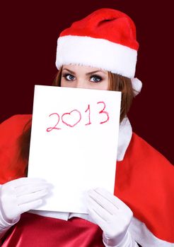 Girl in Santa's hat holding a sheet of paper with the inscription 2013