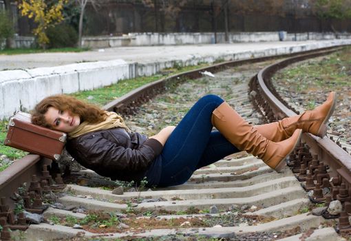 Girl with a suitcase lying on the tracks