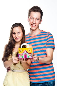 Beautiful and young man and woman holding a colorful toy house in hands